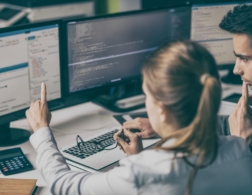 Photo of two young software developers looking at code on a computer screen