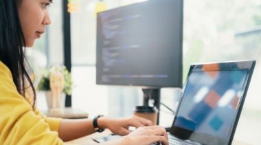 Photo of a young female software developer typing on a laptop