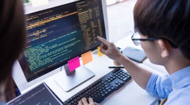 Photo of software developer looking at computer code on screen