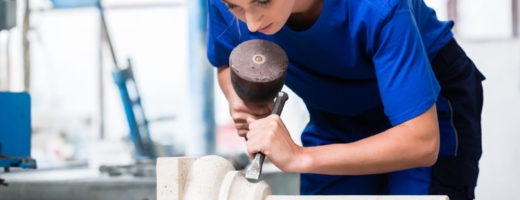 Photo of a young female stonemason with a chisel on part of a pillar