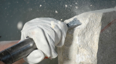 Photo of a stonemason with a chisel on stone