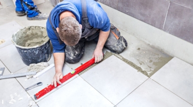 Photo of a tiler using a spirit level to lay floor tiles