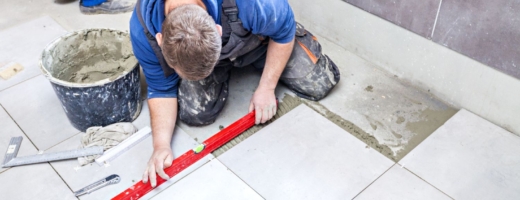 Photo of a tiler using a spirit level to lay floor tiles