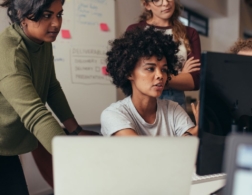 Photo of a group of web designers gathered around a computer screen