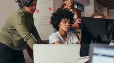 Photo of a group of web designers gathered around a computer screen