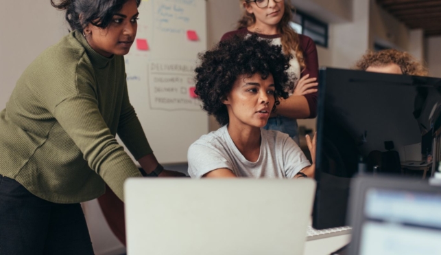 Photo of a group of web designers gathered around a computer screen