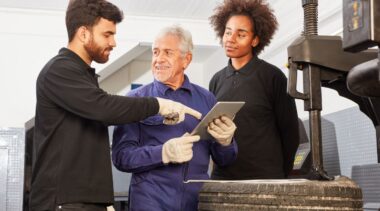 Photo of mechatronics engineers reviewing iPad chart next to machinery