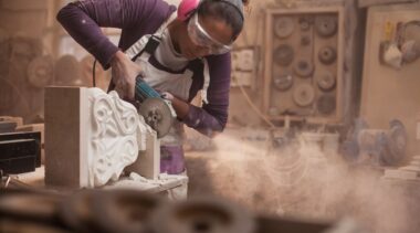 Photo of stonemason using power tool to work on decorative stone item