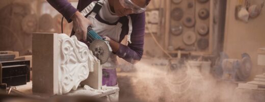 Photo of stonemason using power tool to work on decorative stone item