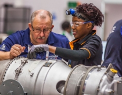 Training manager helping female competitor in aircraft maintenance