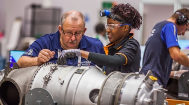 Training manager helping female competitor in aircraft maintenance