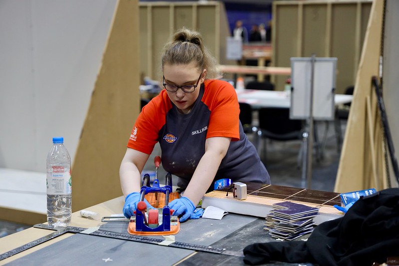 Female tiling competitor cutting tiles