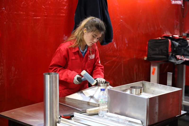 Female competitor hammering metal