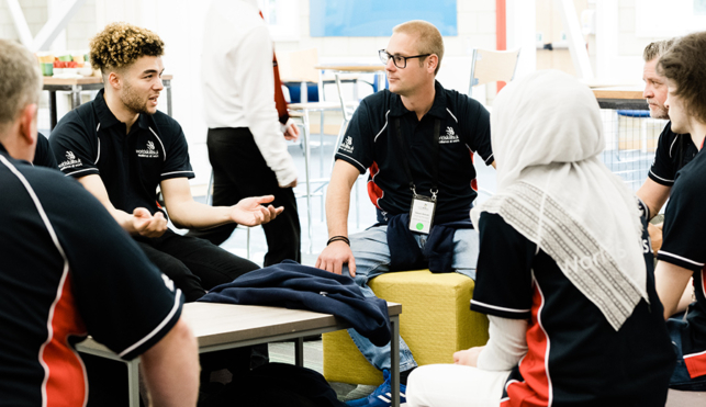 Group of people in WorldSkills UK t-shirts talking