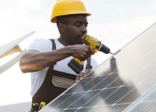 young man fixing solar panels on roof