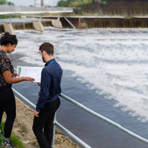 Two people looking at plans next to water