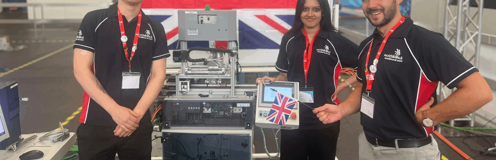 Engineering competitors - two male and a female - smiling at camera with their equipment