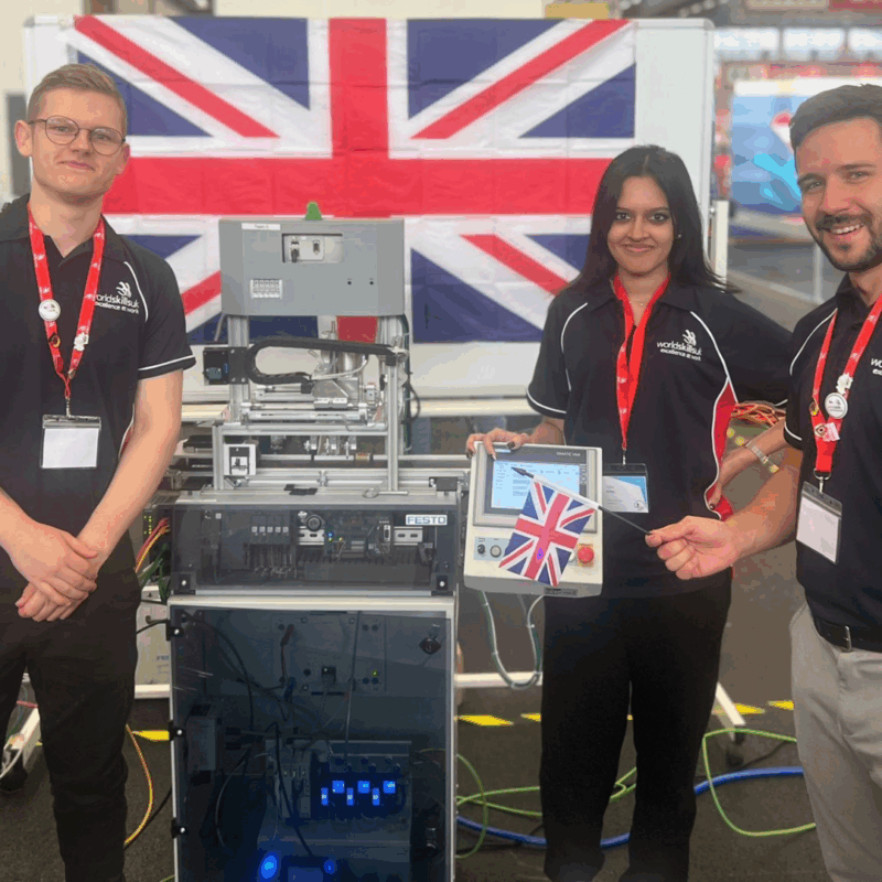 Engineering competitors - two male and a female - smiling at camera with their equipment