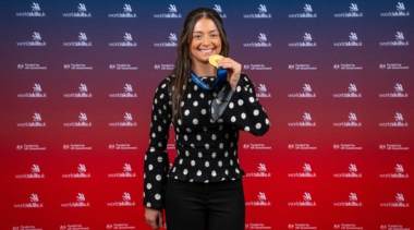 Female gold medal winner in electrical installation 2025 with medal in hand with WorldSkills UK backdrop