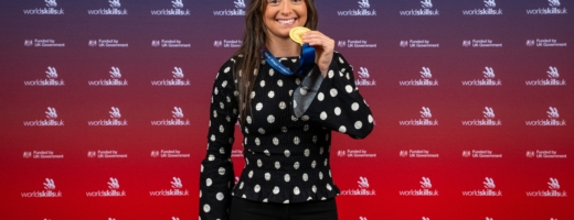 Female gold medal winner in electrical installation 2025 with medal in hand with WorldSkills UK backdrop